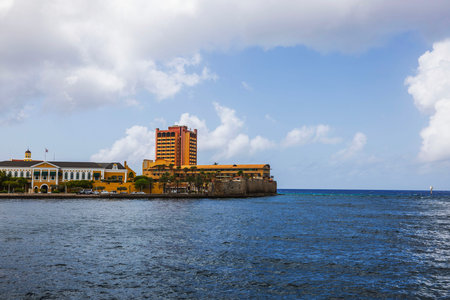 Seaside view of historic waterfront with colonial buildings and tall hotel against Caribbean sea and blue sky with white clouds. Willemstad. Curacao.の写真素材
