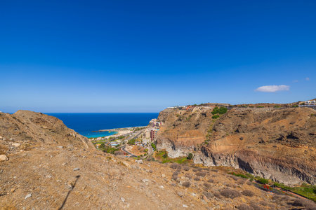 Coastal landscape with rocky hills overlooking Atlantic ocean and beach resort under clear sunny sky.の写真素材