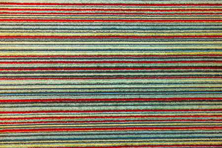 Close up view of striped carpet with textured colorful pattern featuring red, yellow, blue and green horizontal lines.の写真素材