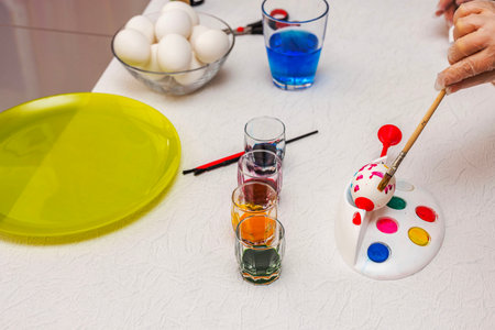Hand painting Easter egg with colorful dyes on white table with brushes and palette. Sweden.の写真素材