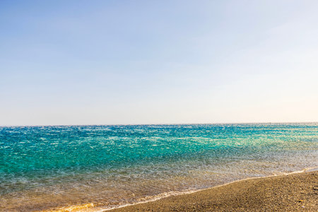 Strong katabatic wind from mountains pushes Aegean sea waves back from shore, creating reverse flow effect under clear sky. Greece.の写真素材