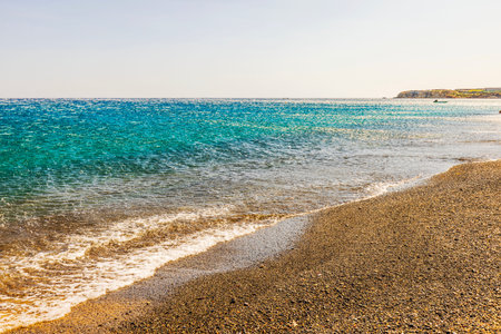 Strong katabatic wind pushes Aegean sea waves back from shore under clear sky, creating a striking reverse flow effect on water. Greece.の写真素材