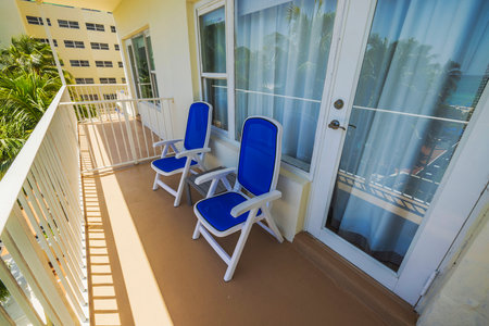 Two blue lounge chairs on hotel balcony overlooking palm trees and Atlantic Ocean in Miami Beach on sunny day. USA.の写真素材