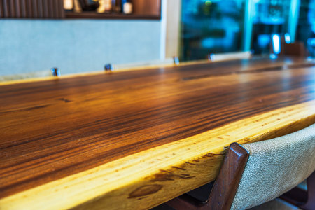 Polished wooden table with natural edges and chairs in hotel lobby, featuring warm tones and modern interior design. Mexico.の写真素材
