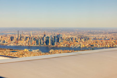 Aerial view of Manhattan skyline from airplane window with Hudson River and skyscrapers in warm sunlight. USA.の写真素材