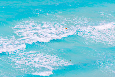 Bright orange buoys floating on turquoise water with white waves and foam under strong wind in tropical waters.の写真素材