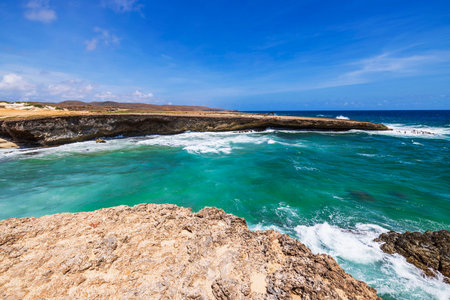 Rocky coastline with turquoise waves Caribbean sea crashing against rugged cliffs in Arikok National Park on sunny day. Aruba.の写真素材