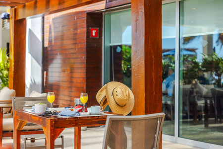 Breakfast table with straw hat and orange juice on outdoor patio of tropical resort near the Caribbean Sea.の写真素材