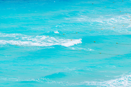 Waves of turquoise Caribbean Sea with floating orange buoys in clear shallow water near beach. Mexico.の写真素材