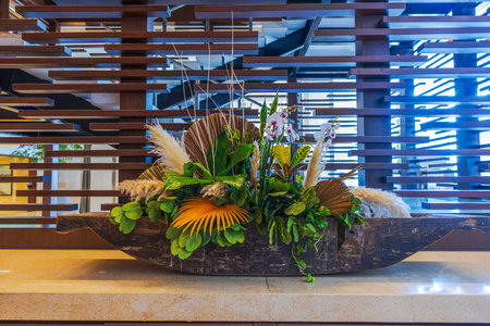 Tropical floral arrangement with orchids dry palm leaves and pampas grass in wooden bowl interior decor. Mexico.の写真素材