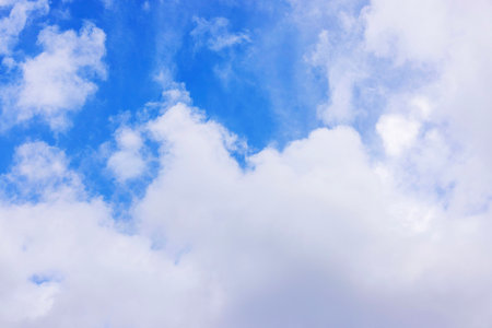 Soft white clouds floating in bright blue sky on sunny day with gentle light and open atmosphere.の写真素材