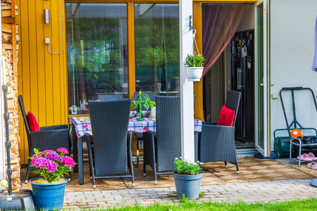 Cozy patio decorated for summer celebration with midsummer pole on table, wicker chairs and potted flowers. Sweden.の写真素材