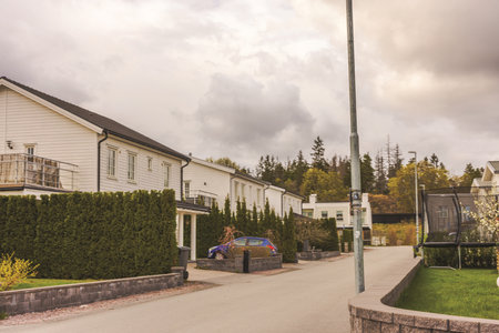 Modern white European villas and trampoline in yard on background of cloudy sky and dense green forest. Sweden.の写真素材