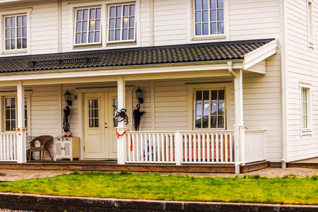 Close up view of front porch of white wooden villa decorated with Halloween figures and orange ribbon in autumn season. Sweden.の写真素材