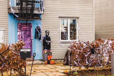 Townhouse entrance decorated for Halloween with skeleton, pumpkins, spider webs and autumn bushes. Sweden.の写真素材