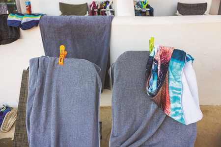 Close up view of drying towels and swimwear on chairs with colorful clips on terrace after pool time in hotel. Greece. Kos.の写真素材