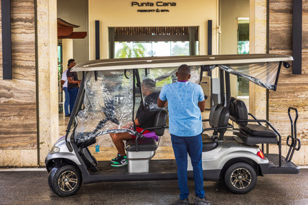 Close-up view of golf cart for tourists covered with plastic film for rain protection at hotel entrance. Dominican Republic. Punta Cana.のeditorial素材