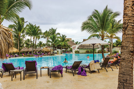 Wonderful view of large resort pool with turquoise water, palm trees and tourists resting near water background. Dominican Republic. Punta Cana.のeditorial素材