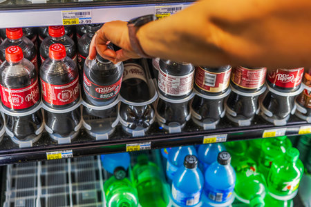 Close up view of woman hand taking Dr Pepper Zero Sugar bottle from refrigerated shelf in CVS store. Miami Beach. USA.のeditorial素材