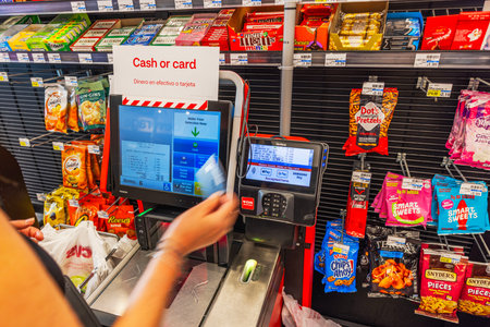 Close up view of woman holding bank card at CVS self checkout kiosk while making payment. Miami Beach. USA.のeditorial素材