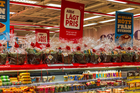 Beautiful view of supermarket shelves with wrapped Christmas gift baskets displayed above food products.のeditorial素材