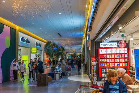 Beautiful view of busy shopping mall corridor with people walking past stores and festive lights.のeditorial素材