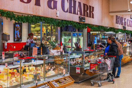 Beautiful view of supermarket deli counter with cheese meat and customers during Christmas season.のeditorial素材