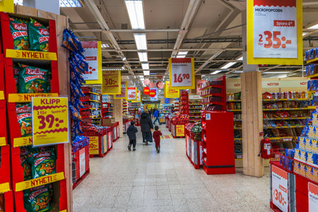 Shoppers walking inside bright supermarket with many discount signs during Christmas season.のeditorial素材