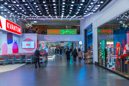 People walking inside bright shopping mall with holiday decorations and colorful store displays.のeditorial素材
