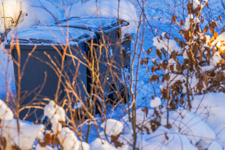Close up view of two snow covered waste bins for garbage sorting in villa garden during winter. Sweden.の写真素材
