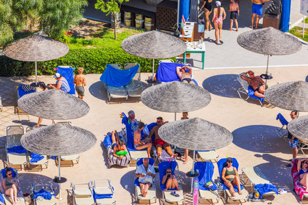 Top view from above of tourists relaxing under sun umbrellas on poolside terrace against background of resort area. Greece. Rhodes.のeditorial素材