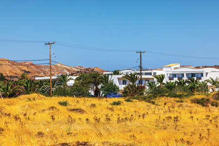 Beautiful view of white villas surrounded by palm trees and dry summer field near Aegean sea. Kos....