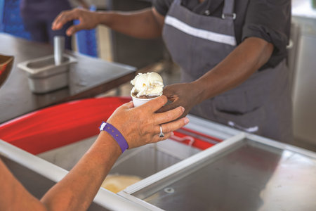 Close up of customer receiving ice cream in cup at street cafe counter. Curacao.
