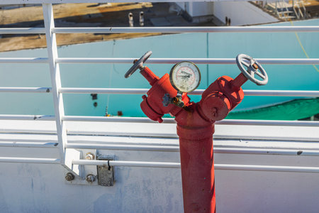 Close up view of red fire hydrant with pressure gauge near white railing on building terrace. Miami Beach. USA.のeditorial素材