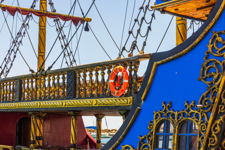 Close up view of pirate style ship deck with ropes mast and lifebuoy in marina on Aegean Sea....