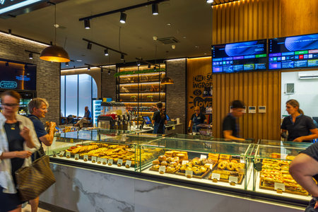Close up view of modern bakery counter with fresh pastries and customers choosing food in cozy cafe...