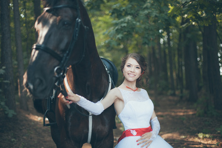 Young woman in white dress standing with horseの写真素材
