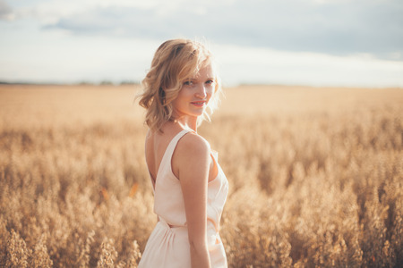Pretty Young woman in Summer Meadow at yellow sunsetの写真素材