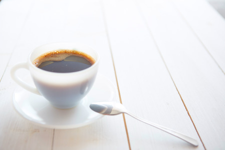 White coffee cup with rich coffee  on a white wooden tableの写真素材