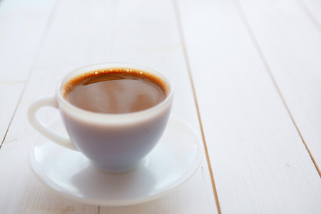 White coffee cup with rich coffee  on a white wooden tableの写真素材