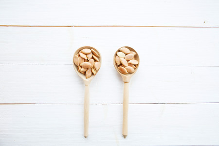 Pumpkin seeds in spoon on white wooden table の写真素材
