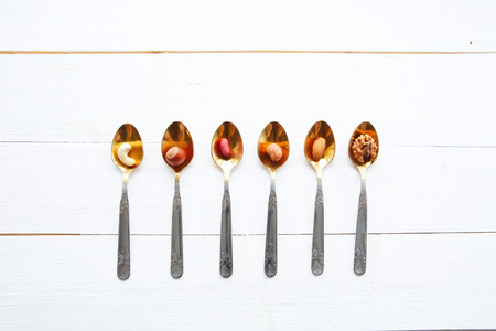 Nuts in spoon on white wooden table の写真素材