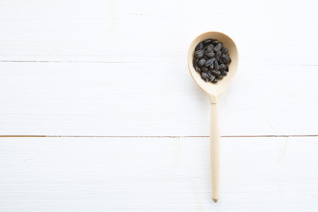 Sunflowers seeds in spoon on white wooden table の写真素材