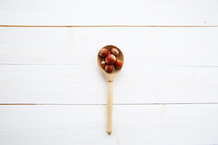 Hazelnuts in spoon on white wooden table の写真素材