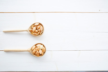 Pumpkin seeds in spoon on white wooden table の写真素材