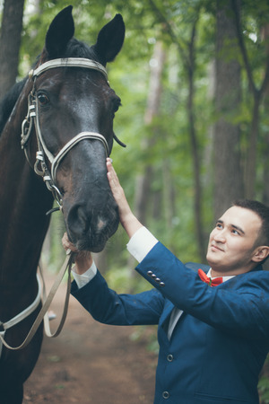 Groom and horse in forestの写真素材