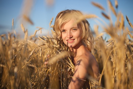 Pretty Young woman in Summer Meadow at yellow sunsetの写真素材