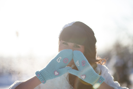 Beautiful bride with a bouquet standing in a snowy winter park at the beautiful snow-covered treesの写真素材