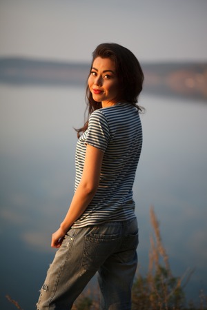 Beautiful woman  near mountain lake. . On the background of the sea. Sunset lightの写真素材