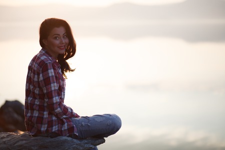 Young woman  sitting by the lake in the woodsの写真素材